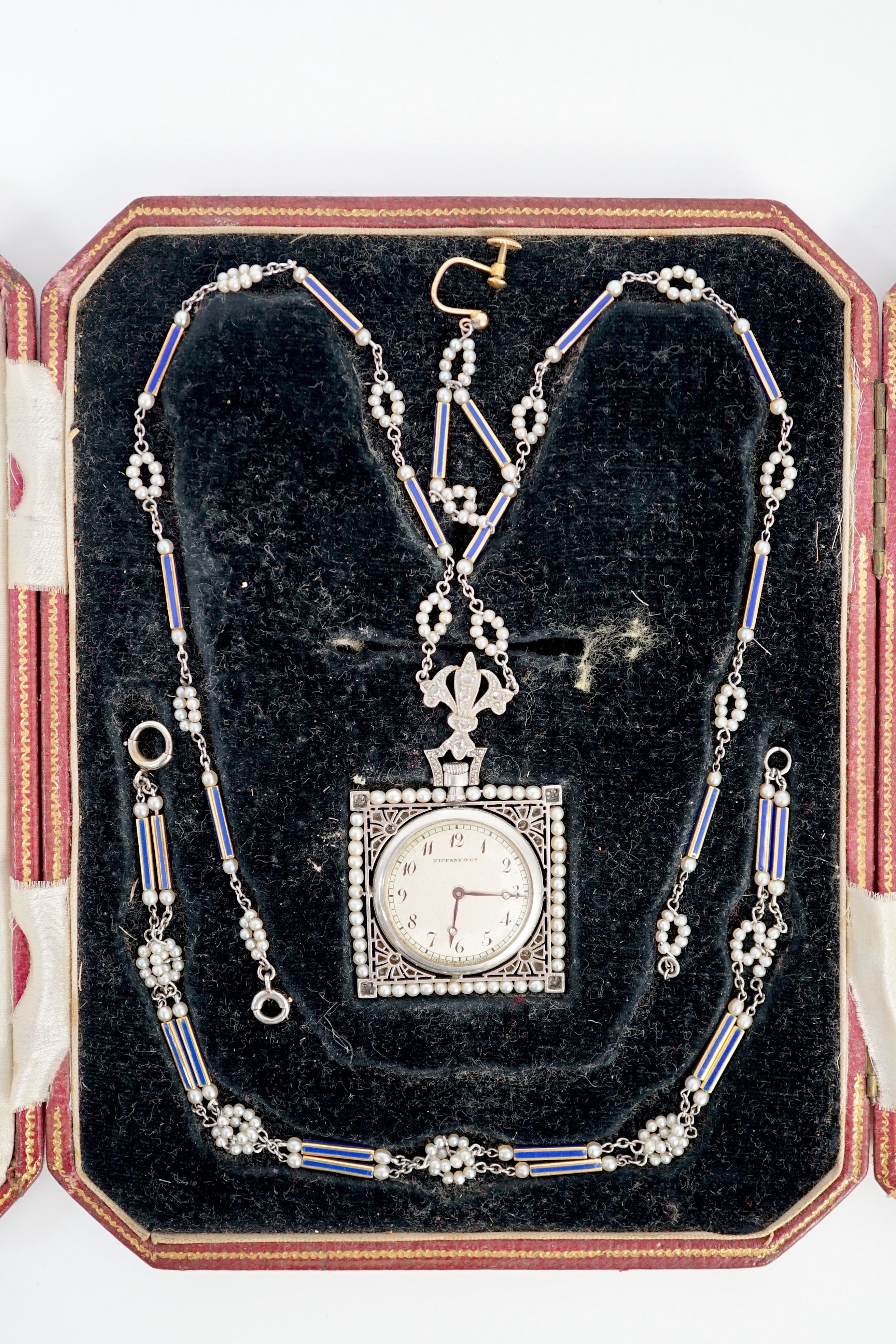 An early 20th century Tiffany & Co platinum, seed pearl and diamond set pendant square open faced dress timepiece, on a platinum, gold, enamel and seed pearl set chain, together with a matching 9ct bracelet and 9ct earri